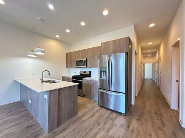 a kitchen with stainless steel appliances granite countertop a refrigerator a sink dishwasher and a stove with wooden floors