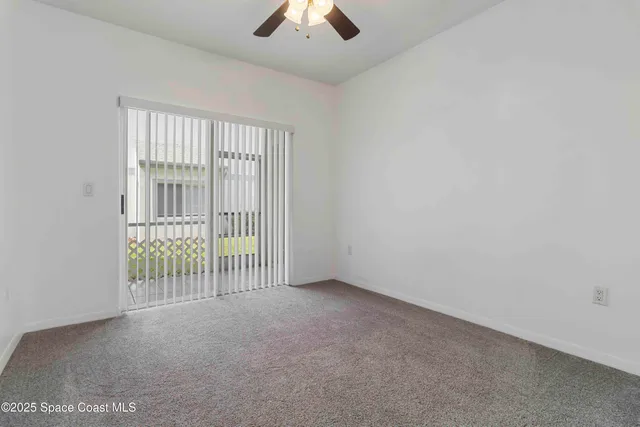 an empty room with a ceiling fan and windows