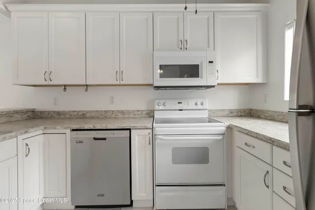 a kitchen with granite countertop white cabinets and white appliances
