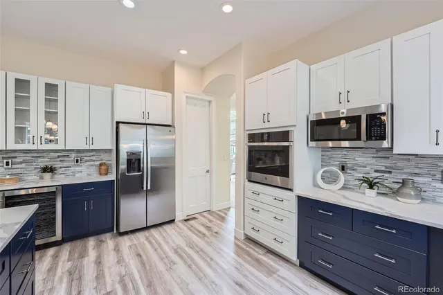 a kitchen with stainless steel appliances a refrigerator cabinets and wooden floor