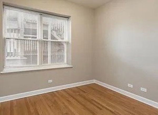 3707 North Kenneth Avenue, Unit 216 Chicago, IL 60641 - Photo 5 of 14 a view of an empty room with wooden floor and a window
