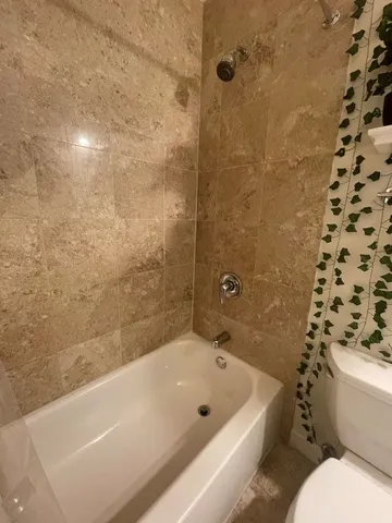 a bath tub sitting next to a white toilet and a shower
