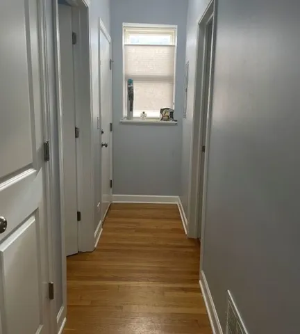 a view of a hallway with wooden floor and a mirror