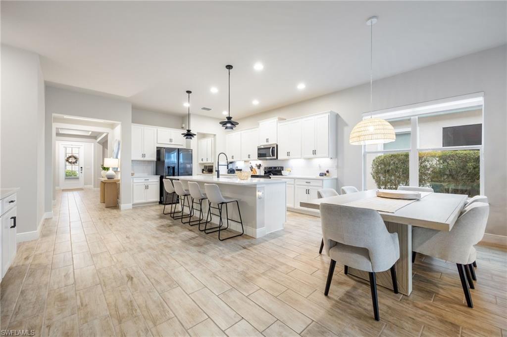 3509 Pilot Circle Naples, FL 34120 - Photo 9 of 50 a kitchen with stainless steel appliances kitchen island granite countertop a table chairs sink and cabinets