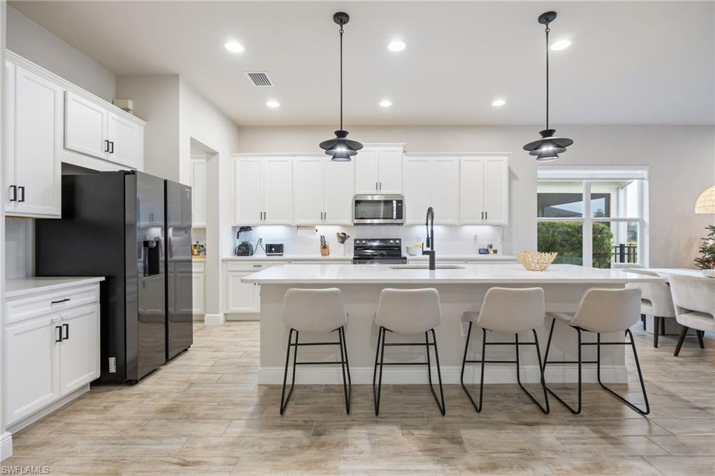 3509 Pilot Circle Naples, FL 34120 - Photo 10 of 50 a kitchen with stainless steel appliances granite countertop a sink a stove a refrigerator cabinets and chairs