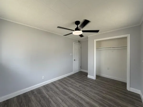 a view of a room with wooden floor and a ceiling fan