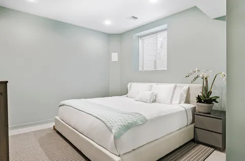 a view of a house with brick walls plants and large tree