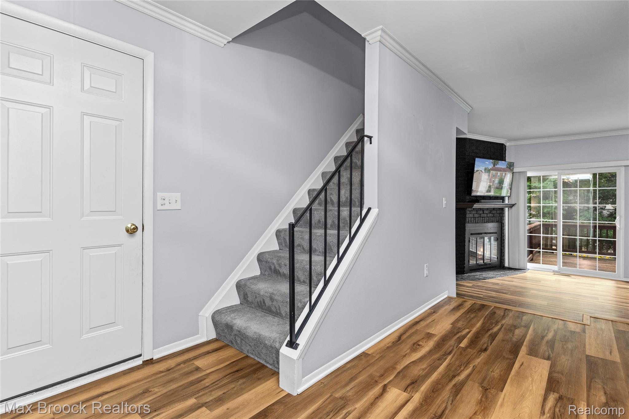 1157 Pine Ridge Court Rochester, MI 48306 - Photo 20 of 55 Bright, open foyer featuring hardwood flooring, a contemporary staircase with metal railings and carpeted treads, crisp white six-panel entry door, and abundant natural light from nearby windows