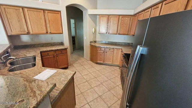 a kitchen with stainless steel appliances granite countertop a refrigerator a stove and a sink with wooden cabinets