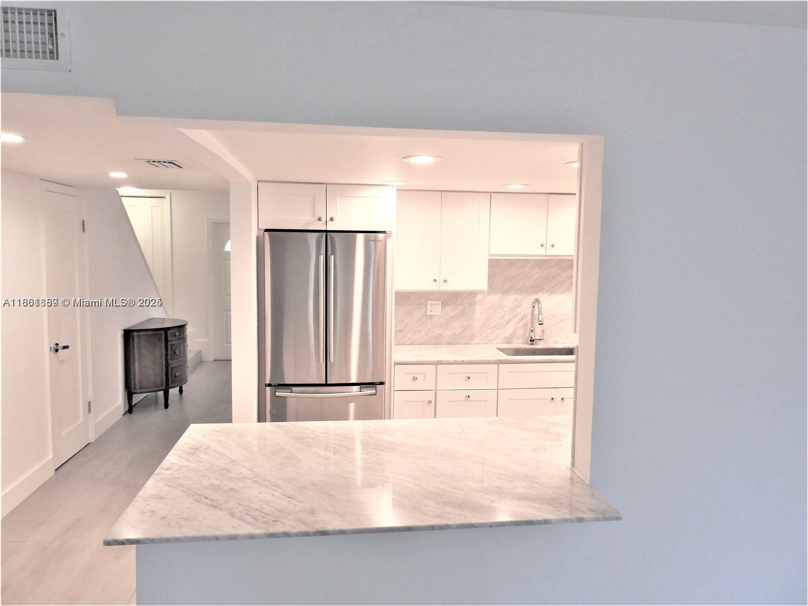 9807 Southwest 93rd Street, Unit 9807 Miami, FL 33176 - Photo 15 of 50 a kitchen with kitchen island a counter top space a sink and a refrigerator