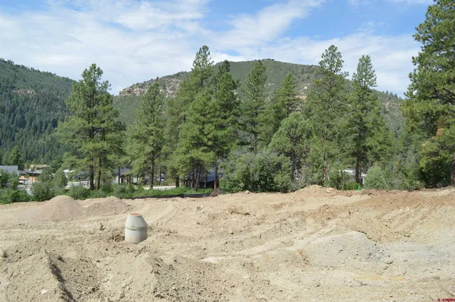 a view of dirt field with trees in the background