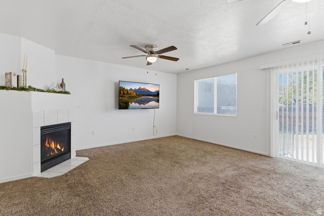 134 West 475 South Ogden, UT 84404 - Photo 11 of 27 Unfurnished living room featuring a ceiling fan, carpet flooring, a tile fireplace, and a textured ceiling