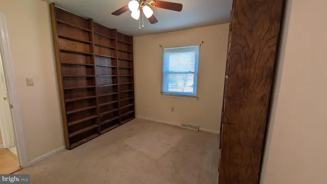 a view of an empty room with a chandelier fan and fire place