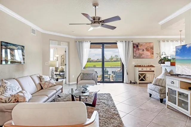 a view of a dining room and livingroom with furniture a rug a flat screen tv and a chandelier