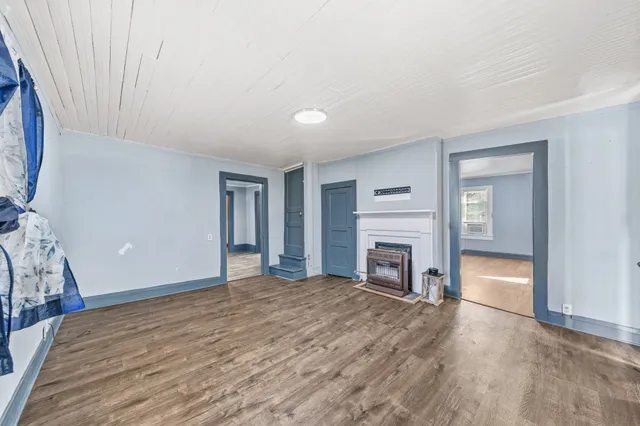 a view of a livingroom with a fireplace a chandelier and windows