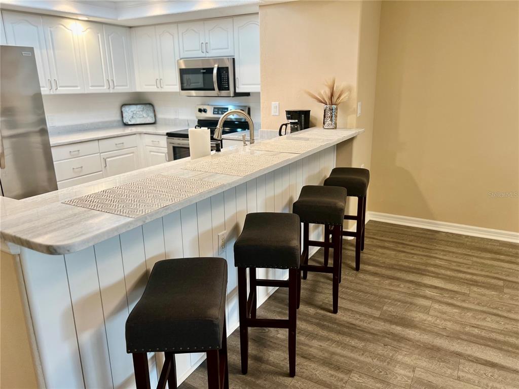 601 Shreve Street, Unit 15B Punta Gorda, FL 33950 - Photo 4 of 29 a kitchen with granite countertop chair and wooden floor