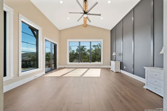 a view of an empty room with a window and wooden floor