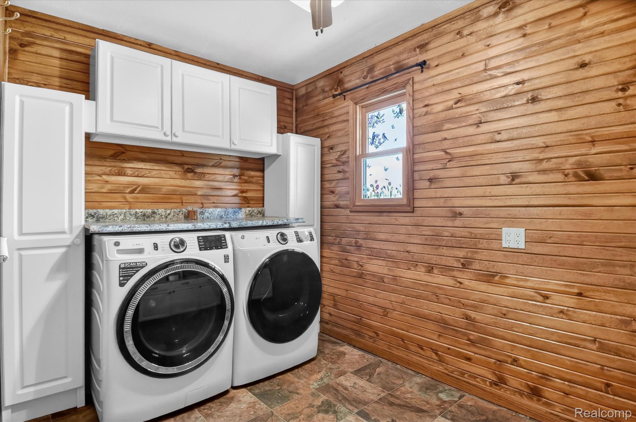 3949 West Burns Line Road Brown City, MI 48416 - Photo 23 of 70 Laundry area featuring wood-paneled walls, white cabinetry, and granite-look countertops