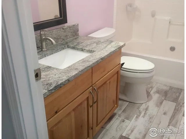 a bathroom with a granite countertop sink toilet and shower