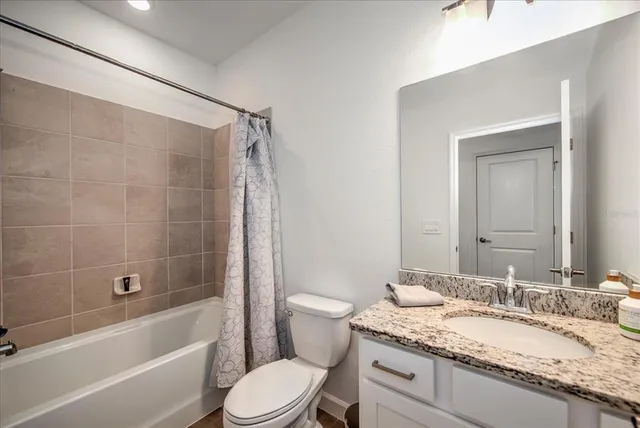 a bathroom with a granite countertop tub sink toilet and mirror