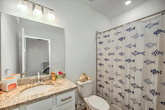 a bathroom with a granite countertop sink a toilet and a mirror