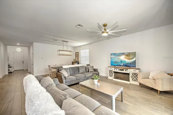 a living room with furniture and a flat screen tv with kitchen view