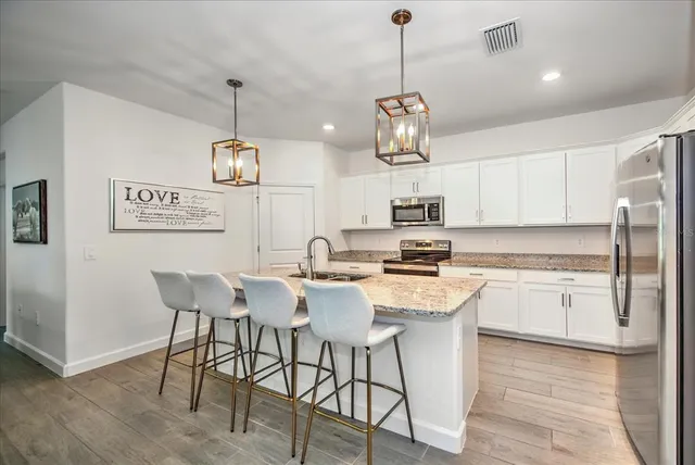 a kitchen with stainless steel appliances granite countertop a kitchen island a stove a table and chairs in it