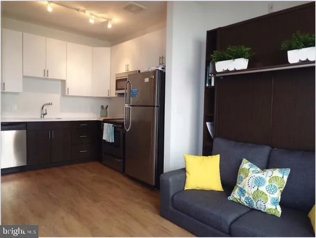 a kitchen with stainless steel appliances kitchen island granite countertop a refrigerator and a sink