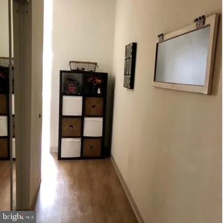 a view of a hallway with wooden floor and cabinet