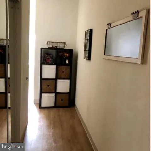 a view of a hallway with wooden floor and cabinet