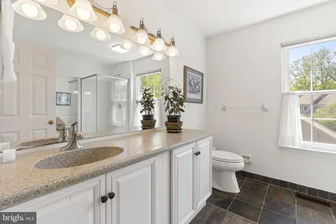 a bathroom with a granite countertop sink a toilet and a mirror
