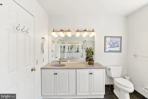 a bathroom with a granite countertop sink a toilet and a mirror