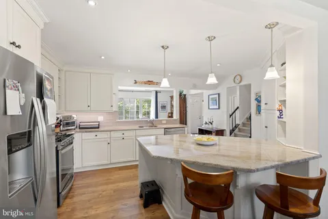 a kitchen with stainless steel appliances granite countertop a kitchen island a stove a table and chairs in it
