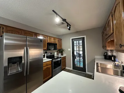 a kitchen with stainless steel appliances granite countertop a refrigerator a stove and a sink with wooden floor