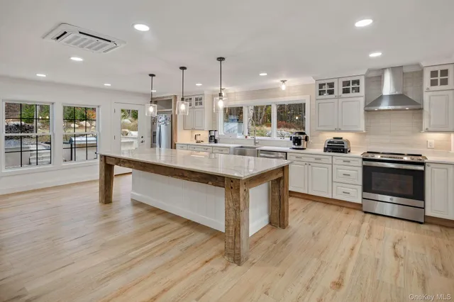a large kitchen with stainless steel appliances granite countertop a stove and a wooden floors
