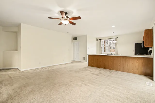 a view of kitchen and empty room with wooden floor