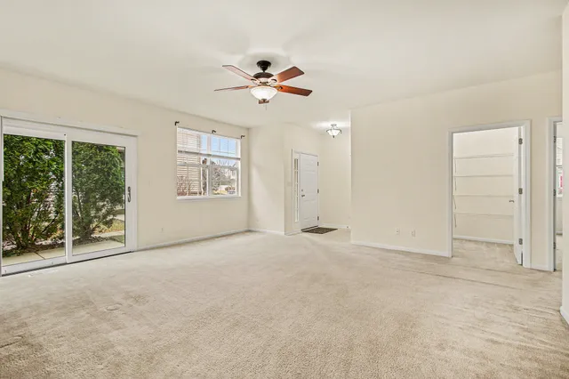 an empty room with windows and ceiling fan