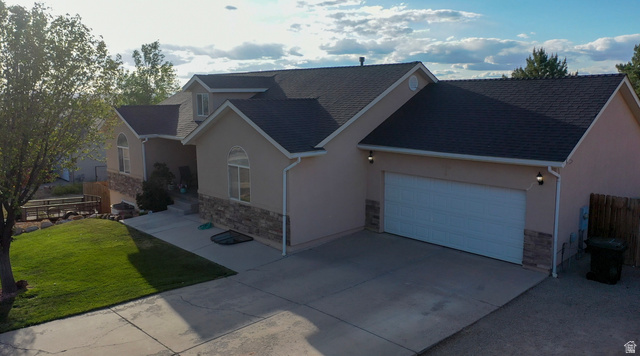 1797 Sunset Road Enoch, UT 84721 - Photo 78 of 80 Stucco and stone exterior featuring a two-car garage, arched windows, and a dark shingle roof