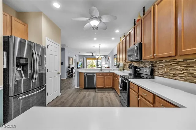 a kitchen with stainless steel appliances granite countertop a refrigerator a sink dishwasher a stove and a sink with wooden floor