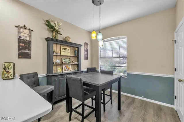 a dining room with wooden floor a chandelier a wooden table and chairs