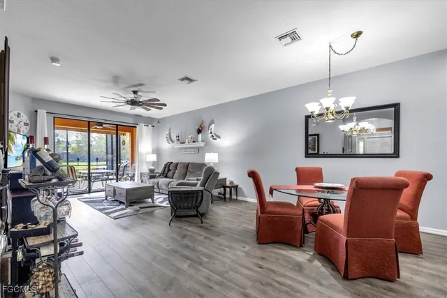 a living room with furniture a chandelier and a dining table with wooden floor