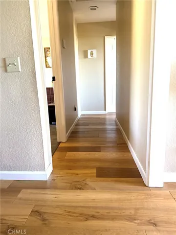 a view of a hallway with wooden floor and a bathroom