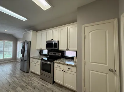 a kitchen with stainless steel appliances white cabinets and a refrigerator