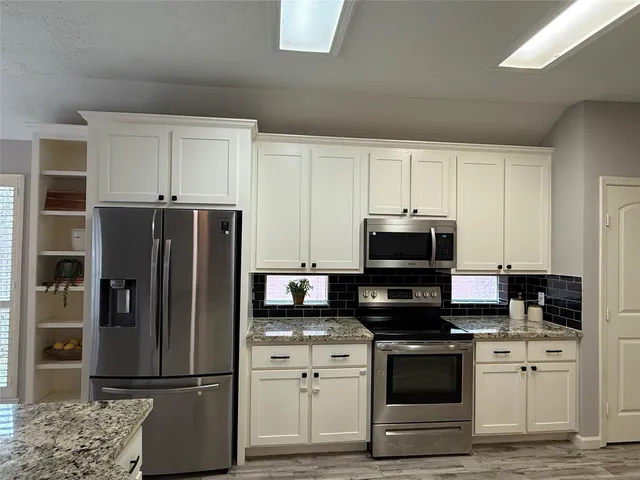 a kitchen with stainless steel appliances granite countertop a refrigerator stove and microwave
