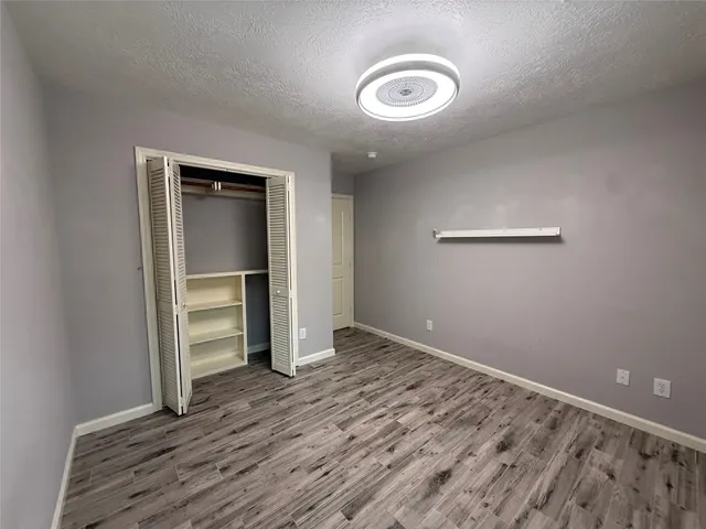 an empty room with wooden floor closet and windows
