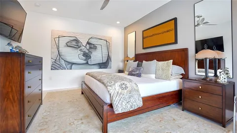 a bedroom with a bed television on wall and a flat tv screen