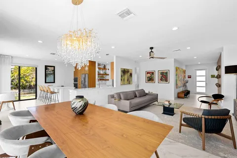 a living room with furniture kitchen view and a chandelier