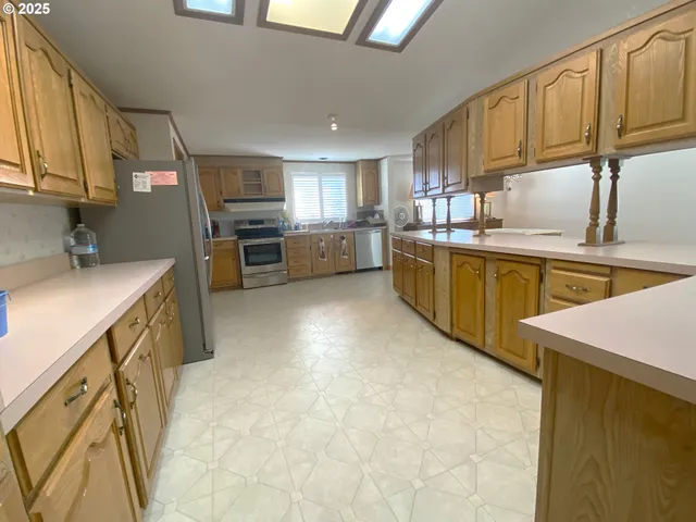 a kitchen with stainless steel appliances granite countertop a refrigerator a sink and white cabinets