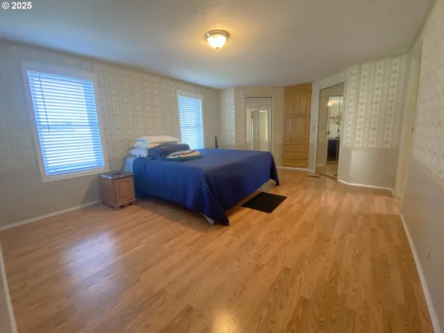 a spacious bedroom with a bed and wooden floor