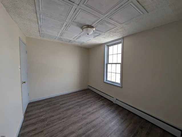 an empty room with wooden floor and a ceiling fan